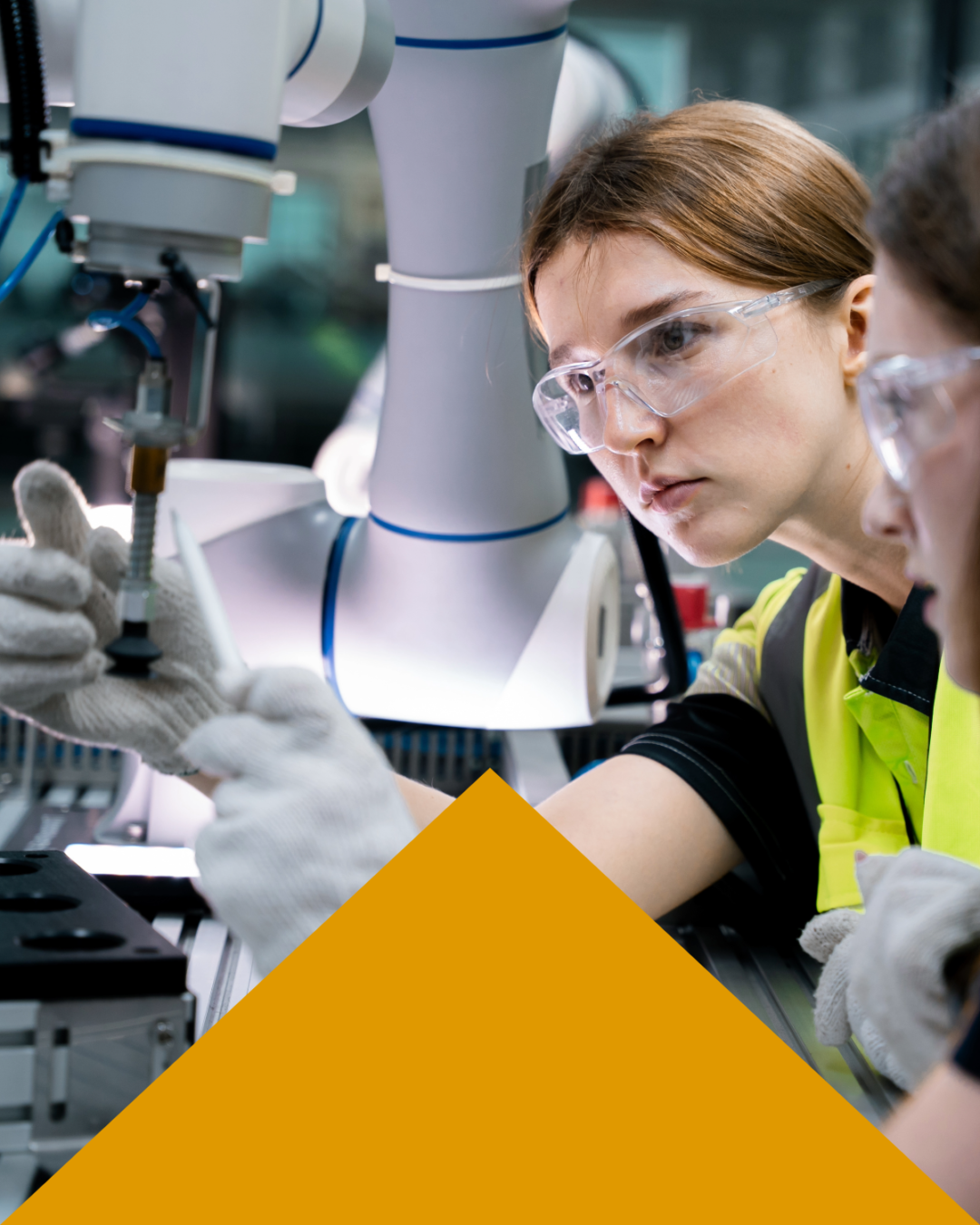 Female maintenance engineer in safety glasses working on a robotic arm