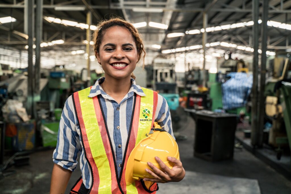 Smiling production worker in a hi-vis vest on a UK site
